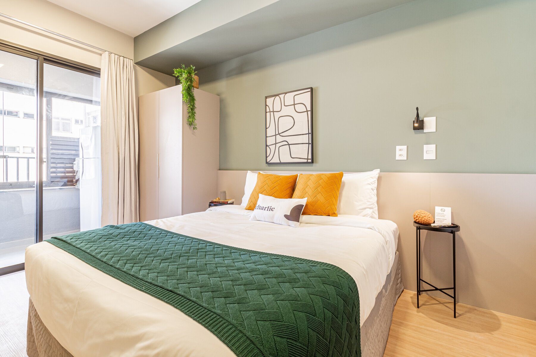 Quarto moderno com cama confortável, decoração em tons suaves e detalhes com plantas, ideal para um descanso tranquilo.