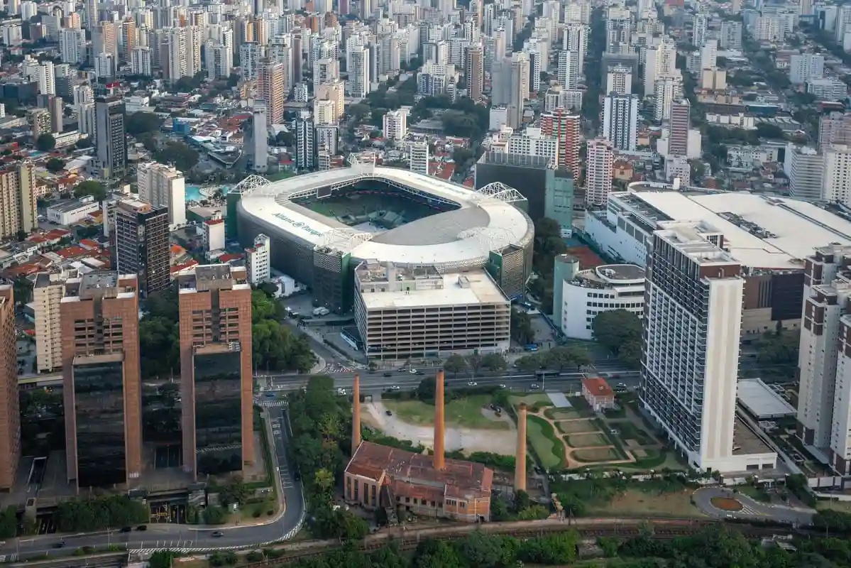 Vista aérea do Estádio do Morumbi em São Paulo, cercado por edifícios e infraestrutura urbana, com destaque para seu formato distinto e amplo entorno.